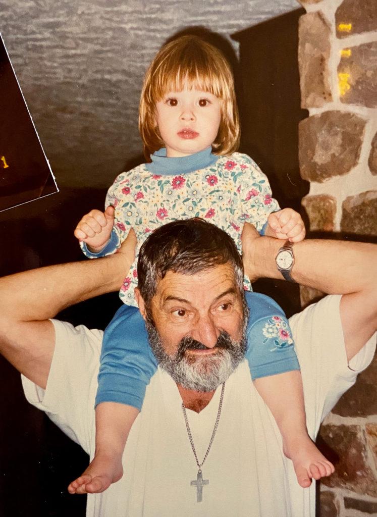 A grandfather holds his granddaughter on this shoulders.